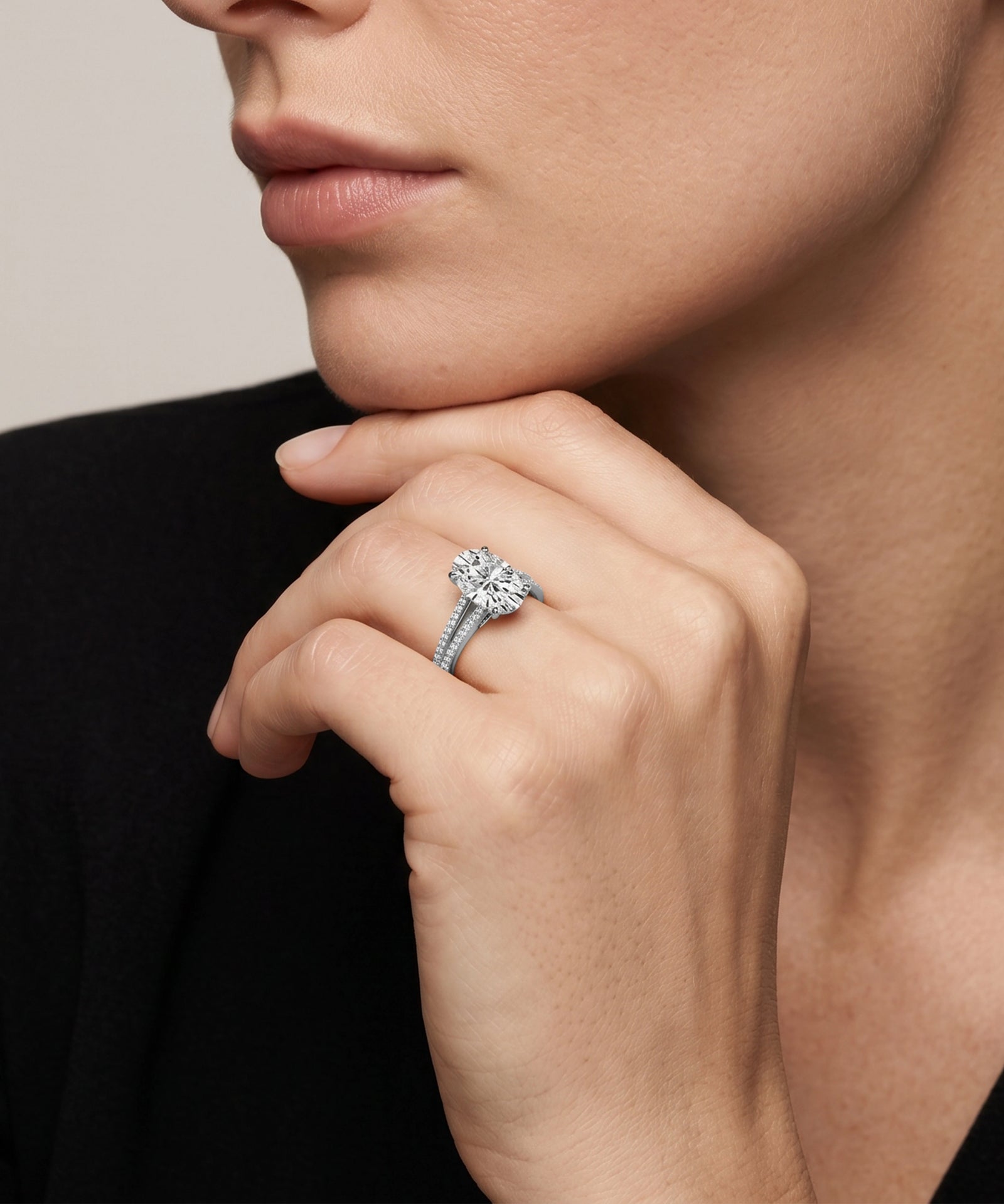 Close-up of a hand wearing a diamond ring with a neutral background