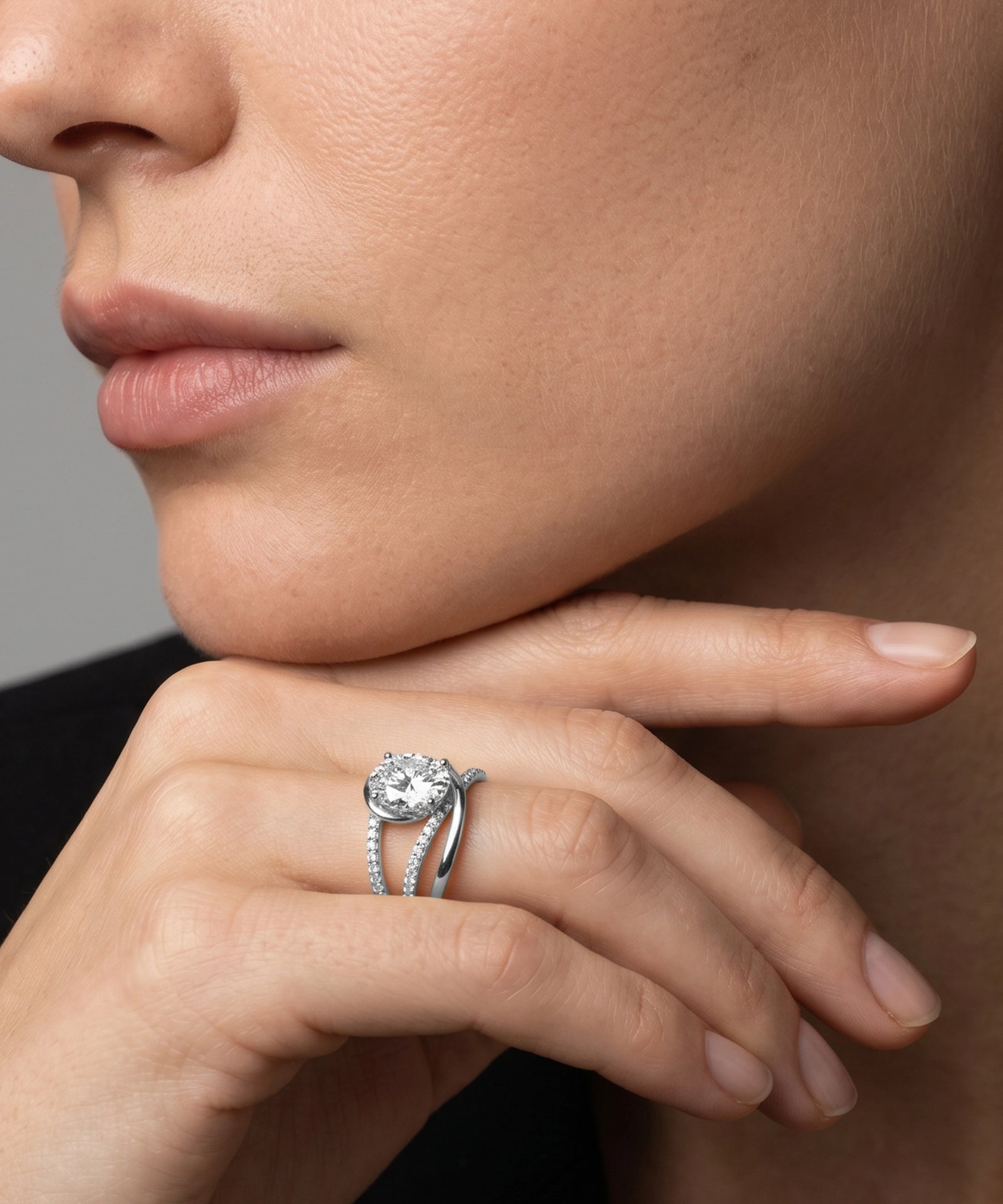 Close-up of a hand wearing a diamond ring with a neutral background