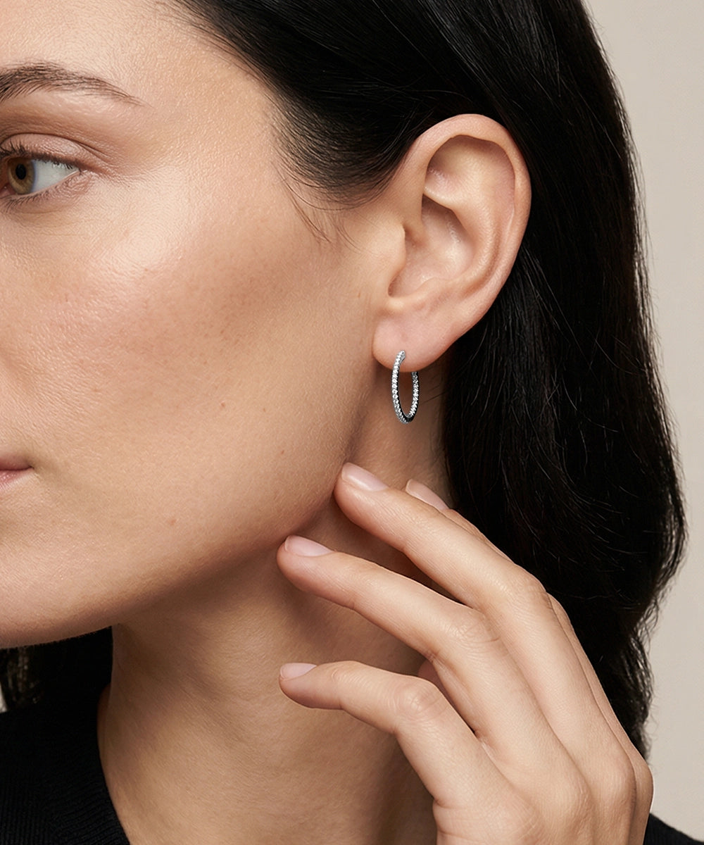 Close-up of a woman wearing a silver hoop earring with a neutral background