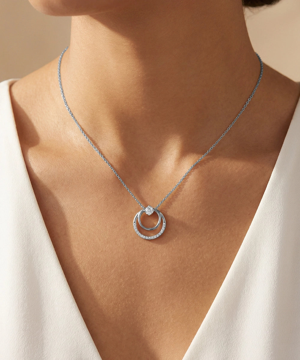 Silver necklace with a pendant on a person wearing a white top.
