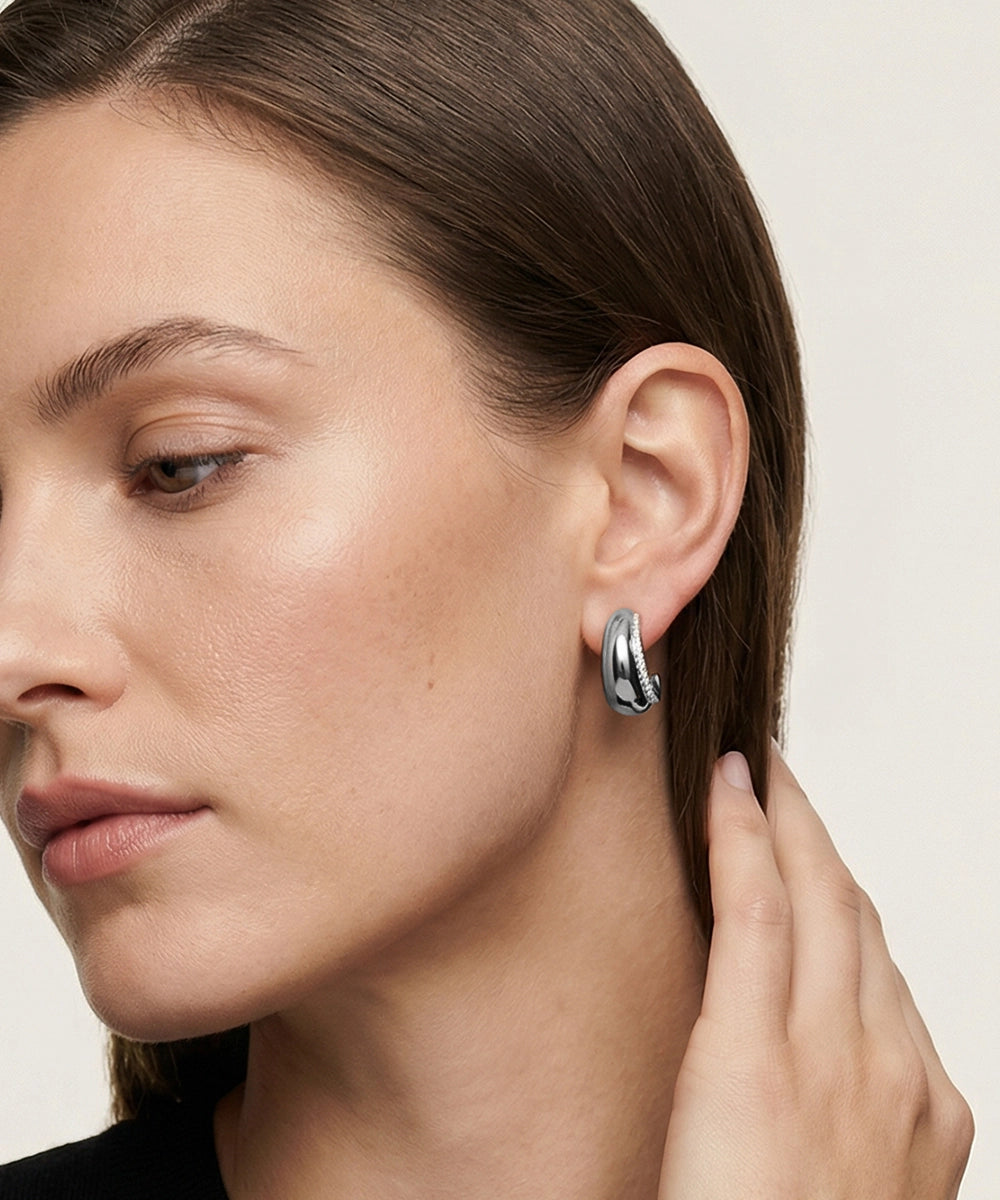 Close-up of a woman wearing a silver earring with a neutral background