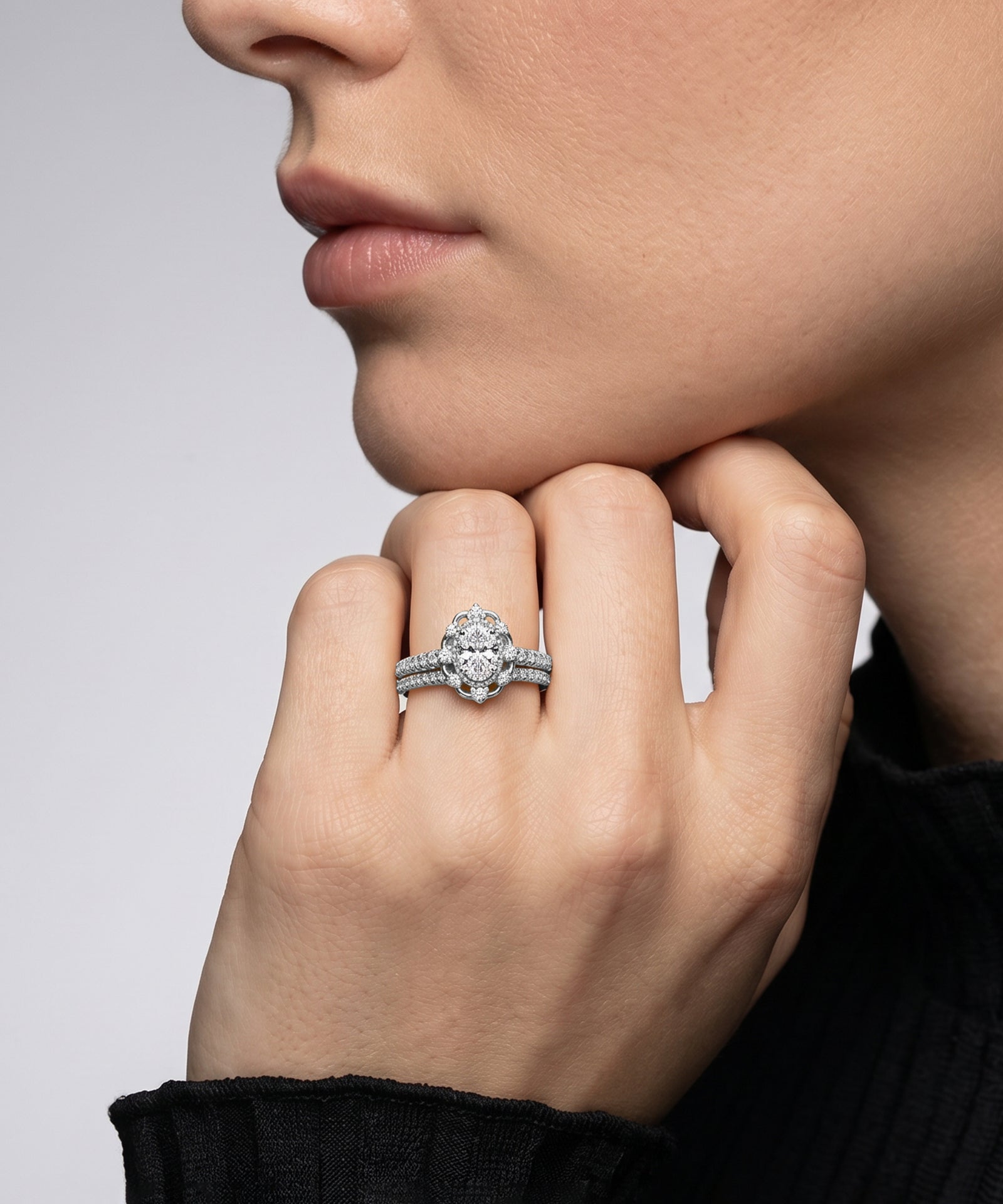 Close-up of a hand wearing a diamond ring with a neutral background