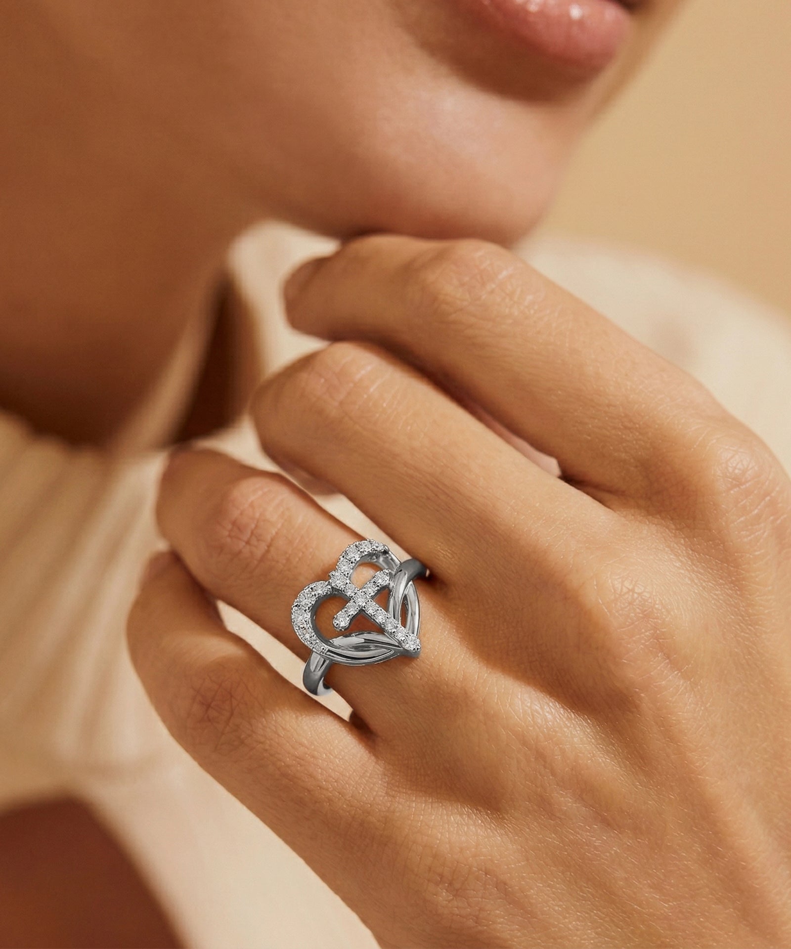 Silver ring with intricate design on a person's finger against a neutral background