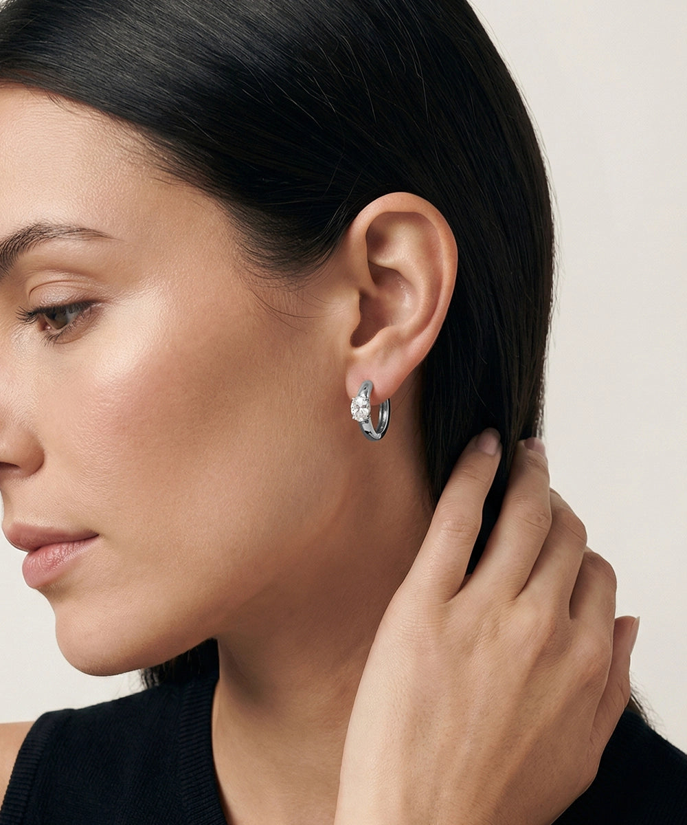 Close-up of a woman wearing a silver hoop earring with a neutral background