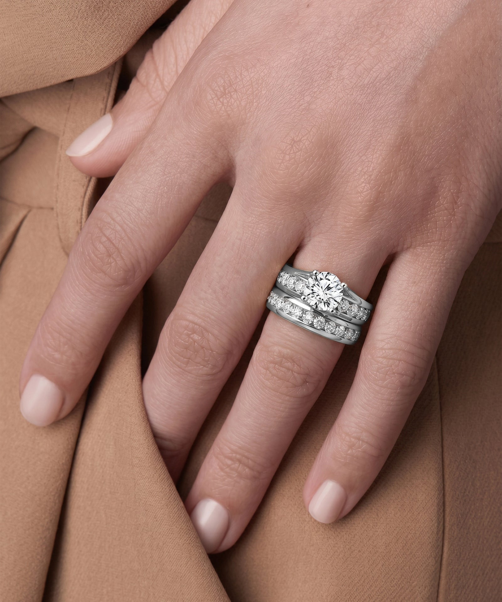 Close-up of a hand wearing two diamond rings on a brown fabric background