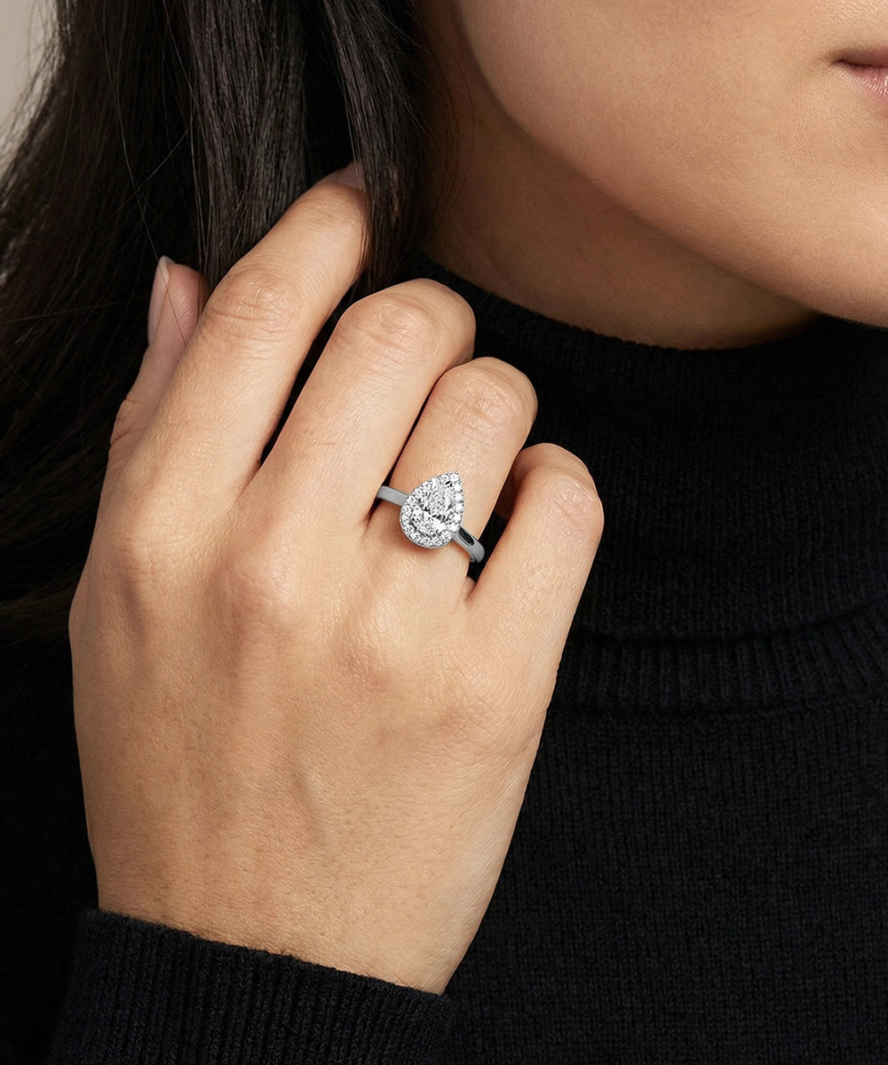 Close-up of a hand wearing a diamond ring with a blurred background