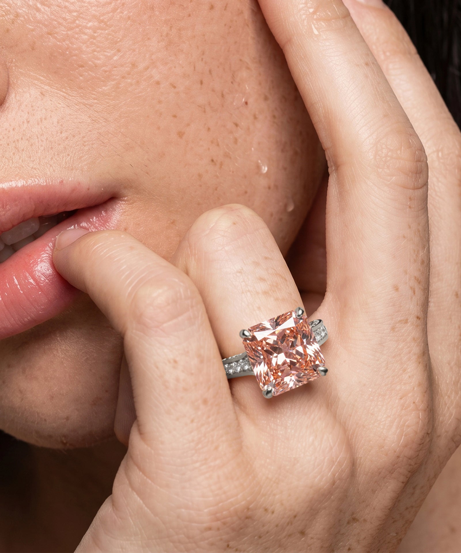 Close-up of a hand wearing a pink gemstone ring with a blurred background