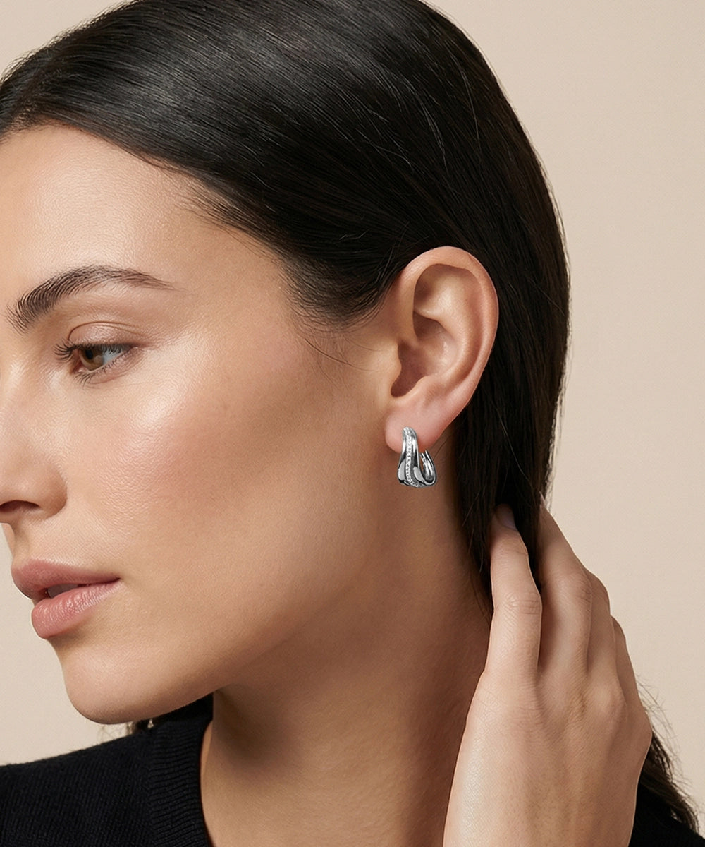 Close-up of a woman wearing silver earrings with a neutral background