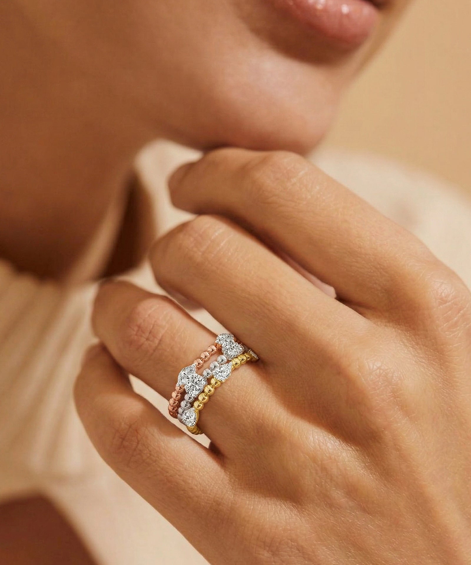 Close-up of a hand wearing a gold and silver ring on a neutral background