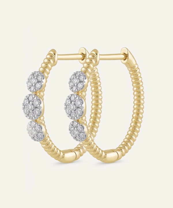Gold hoop earrings with diamond accents on a light beige background