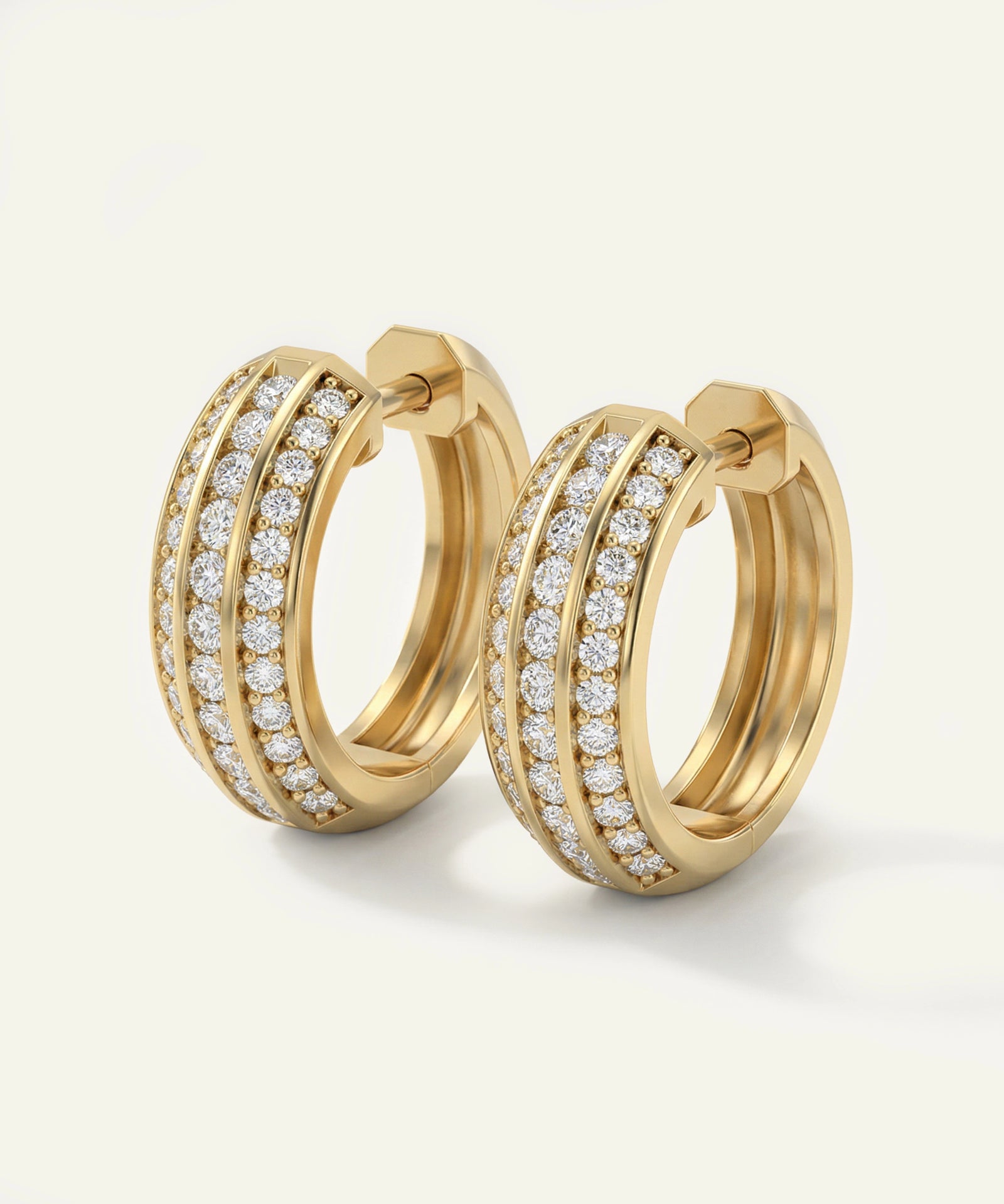 Gold hoop earrings with diamond accents on a light beige background