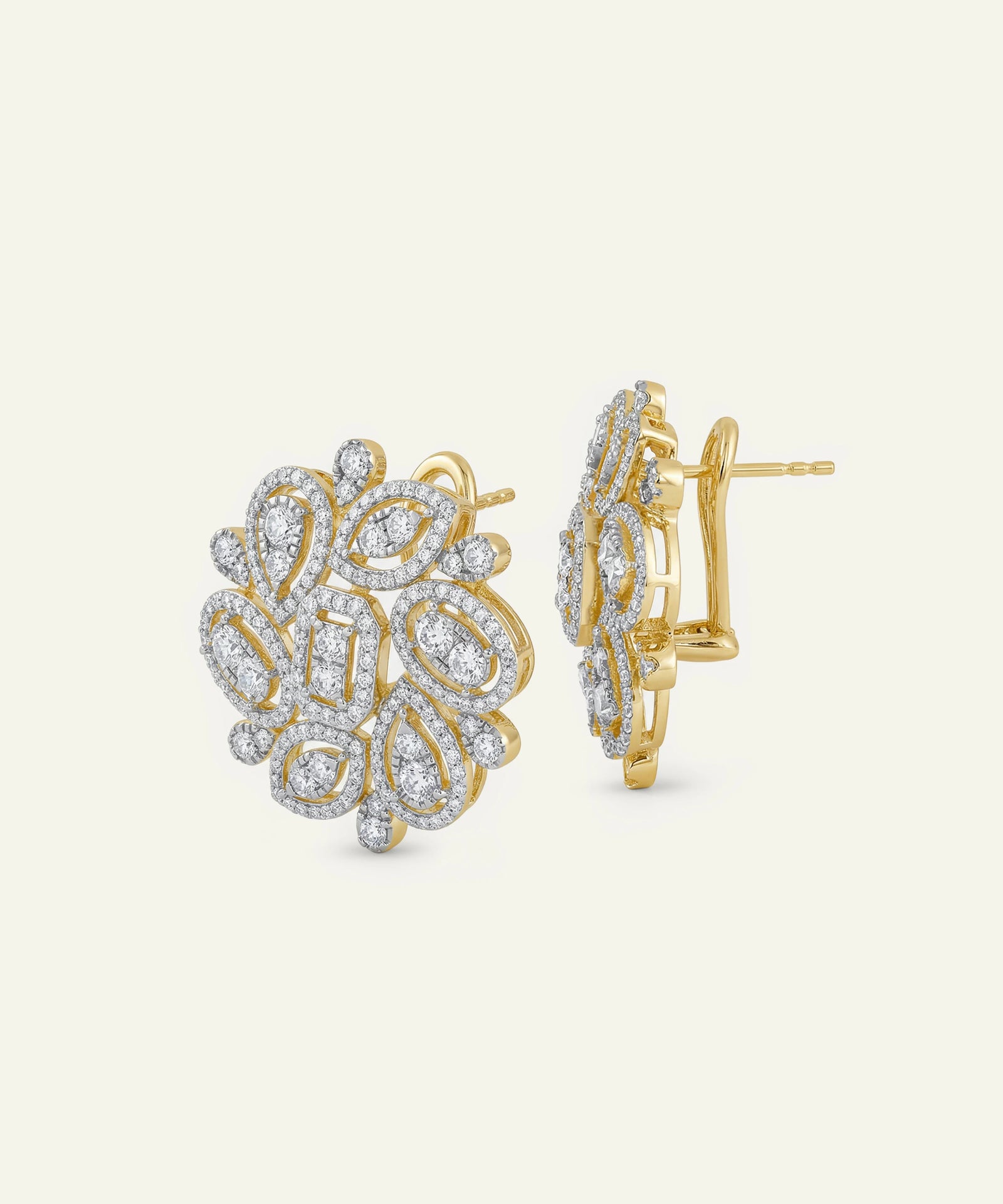 Gold and diamond earrings on a light beige background