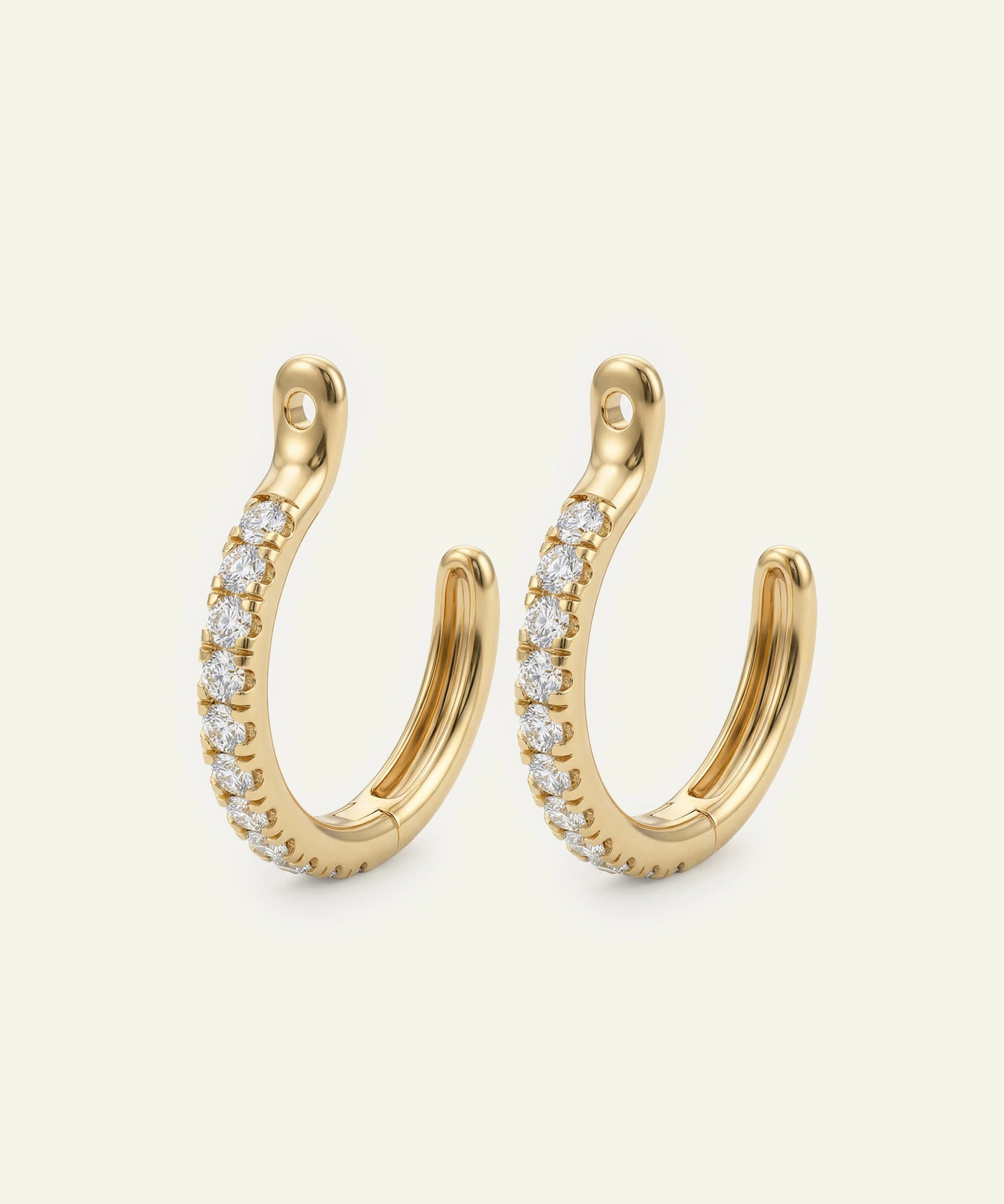 Gold hoop earrings with embedded diamonds on a light beige background