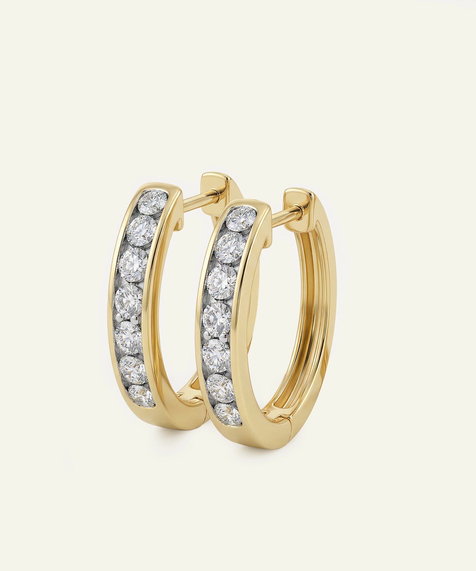 Gold hoop earrings with diamond accents on a light beige background