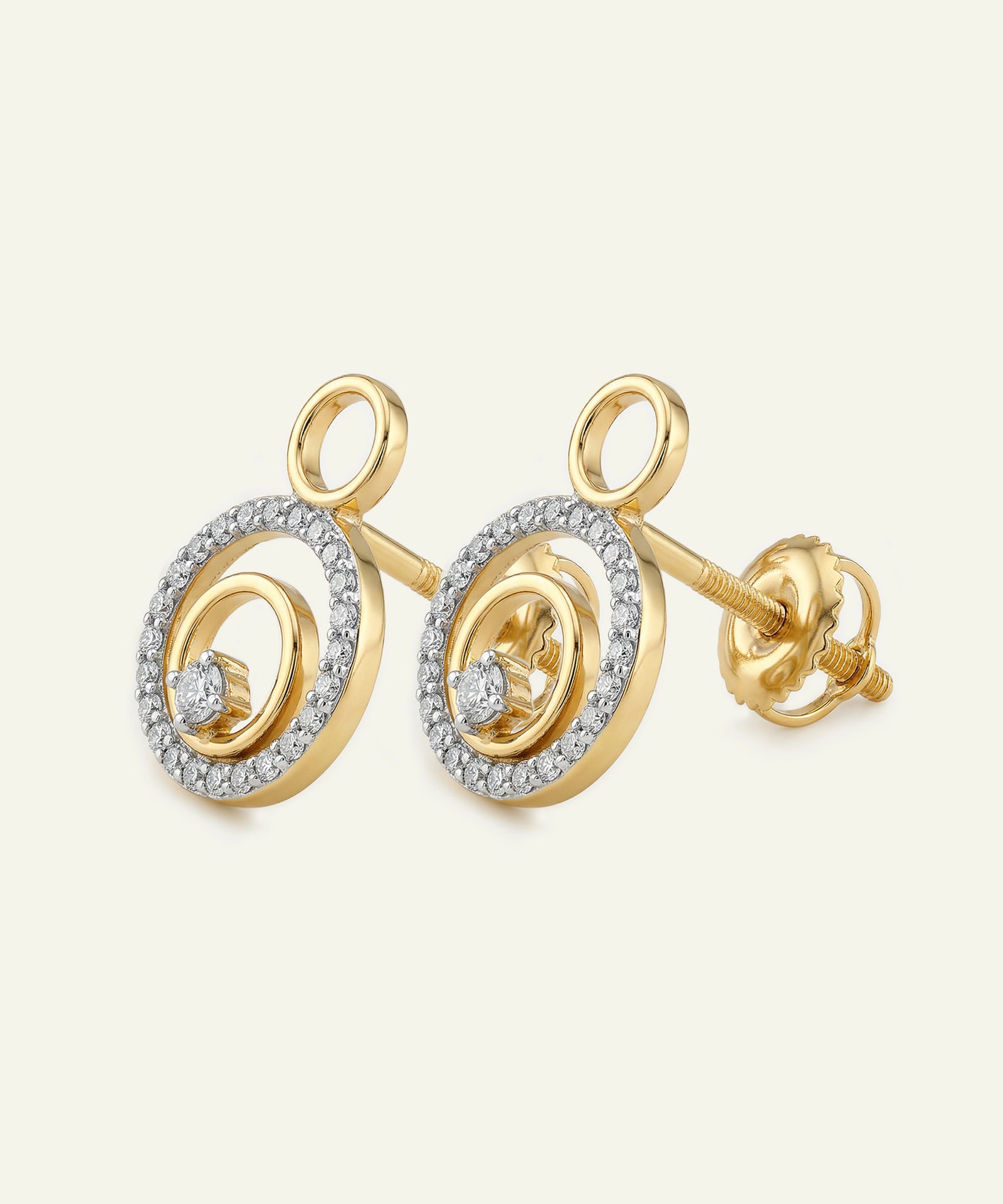 Gold earrings with circular design and embedded stones on a light beige background