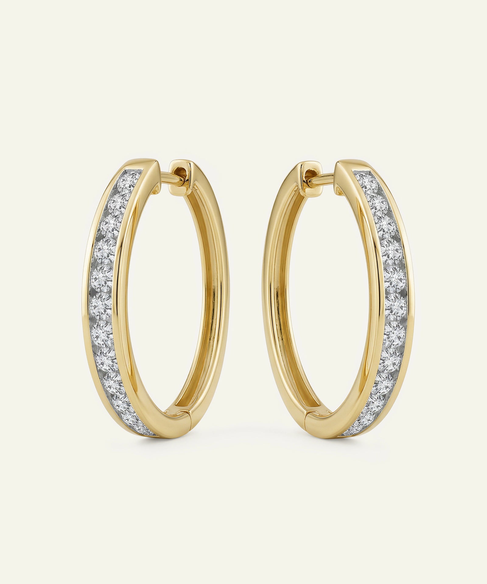 Gold hoop earrings with diamond accents on a light beige background