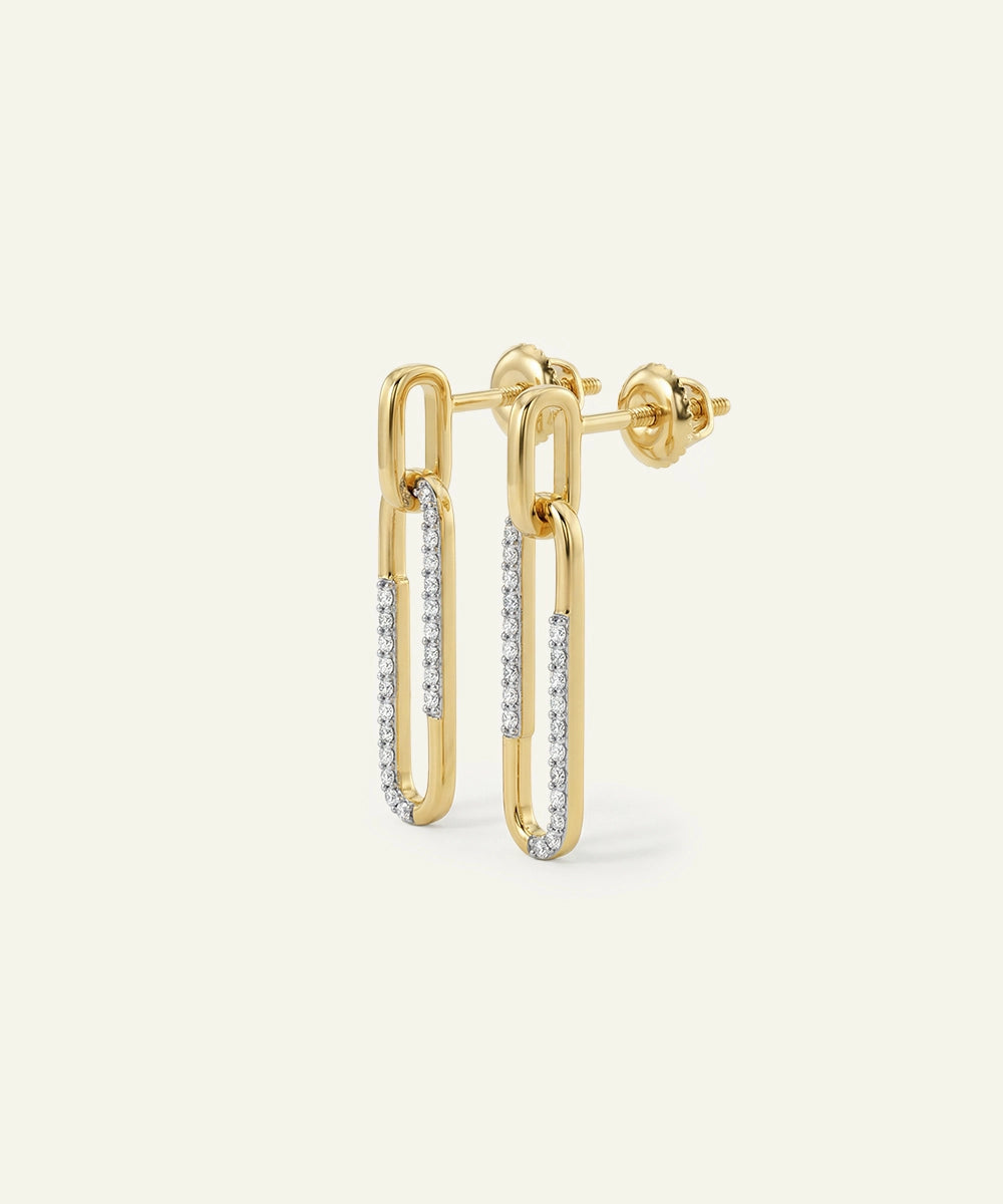 Gold hoop earrings with embedded diamonds on a light beige background