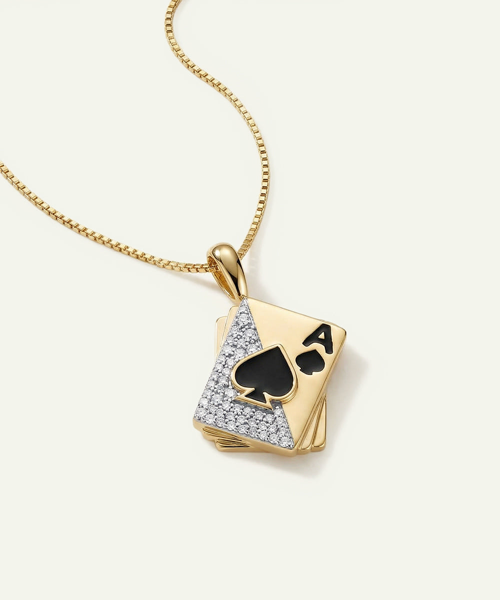 Gold necklace with a playing card pendant featuring a spade symbol on a white background