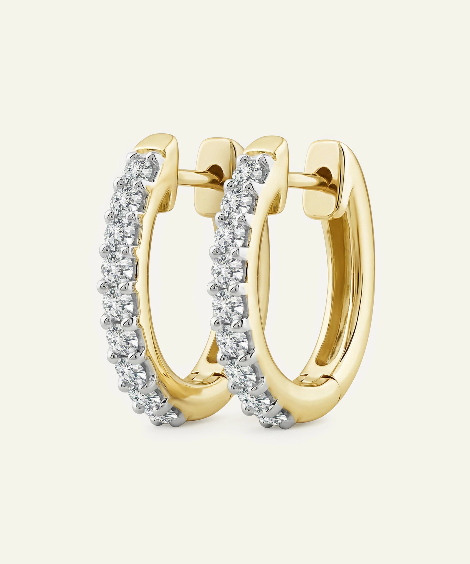 Gold hoop earrings with diamond accents on a light beige background