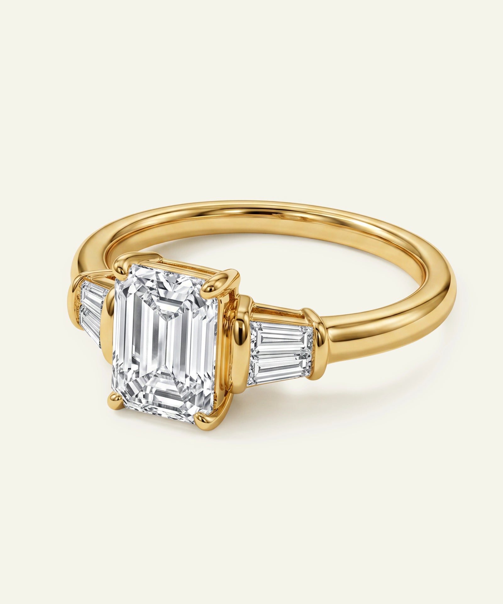 Gold ring with a large emerald-cut diamond and smaller side stones on a light background
