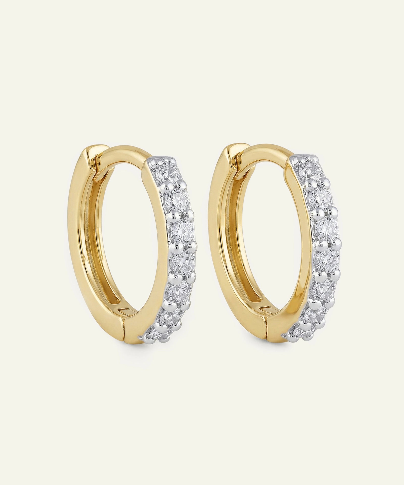 Gold hoop earrings with diamond accents on a light beige background