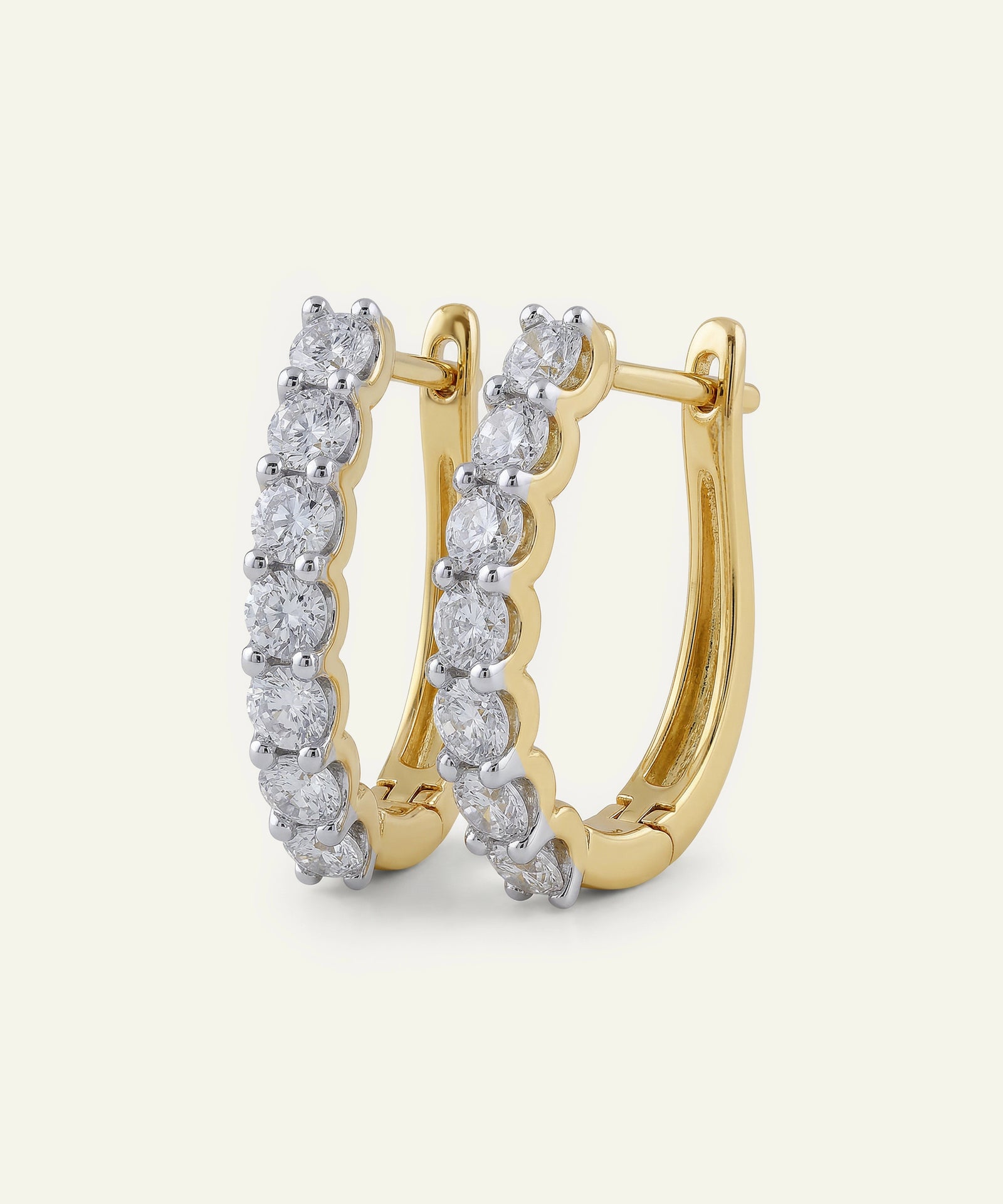 Gold hoop earrings with diamond accents on a light beige background