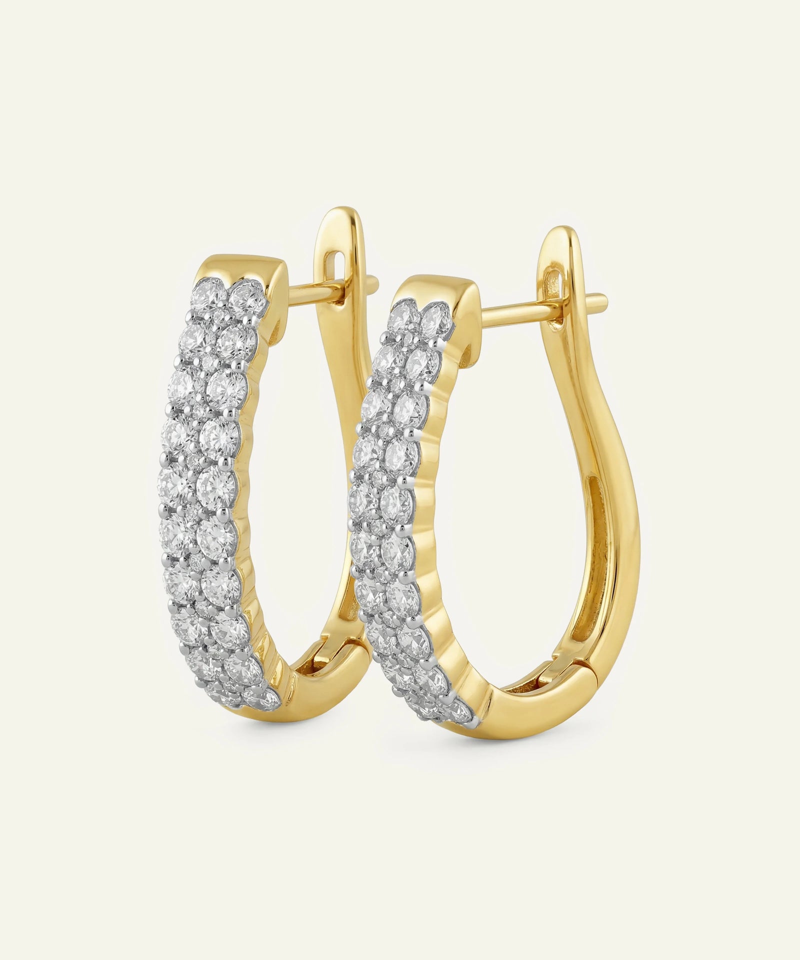 Gold hoop earrings with diamond accents on a light beige background
