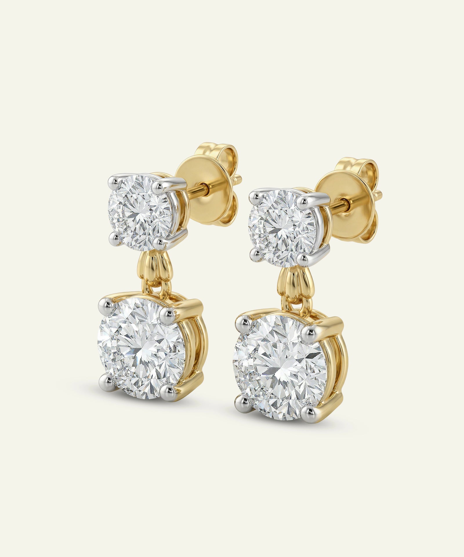 Gold earrings with diamond studs on a light beige background