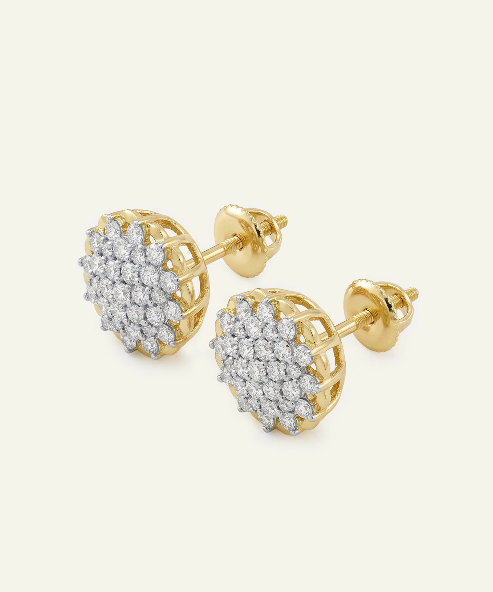 Gold earrings with diamond accents on a light beige background