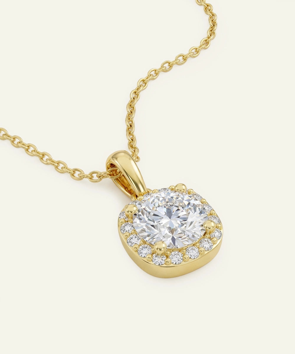 Gold necklace with a diamond pendant on a light beige background