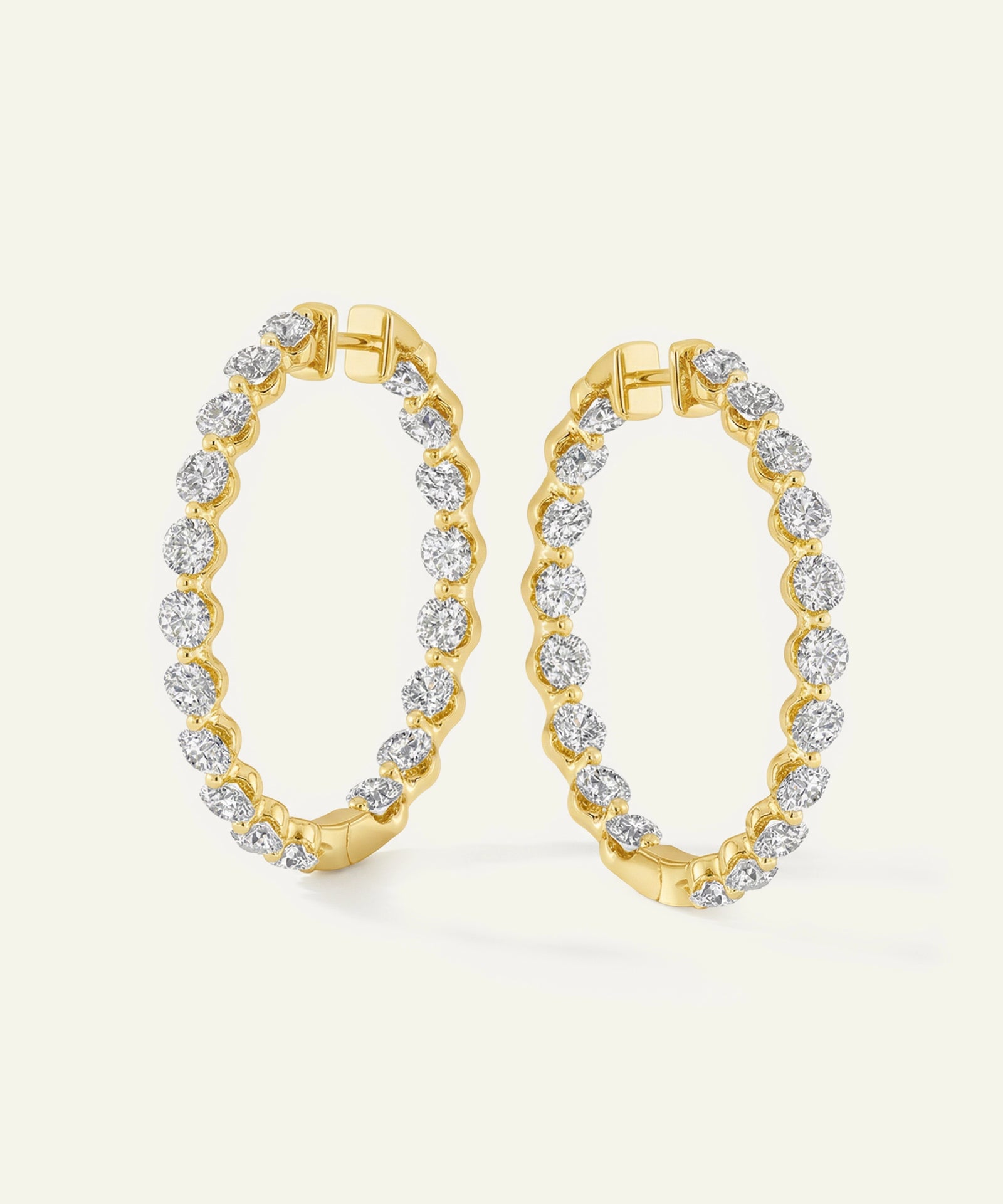 Gold hoop earrings with diamond accents on a light gray background