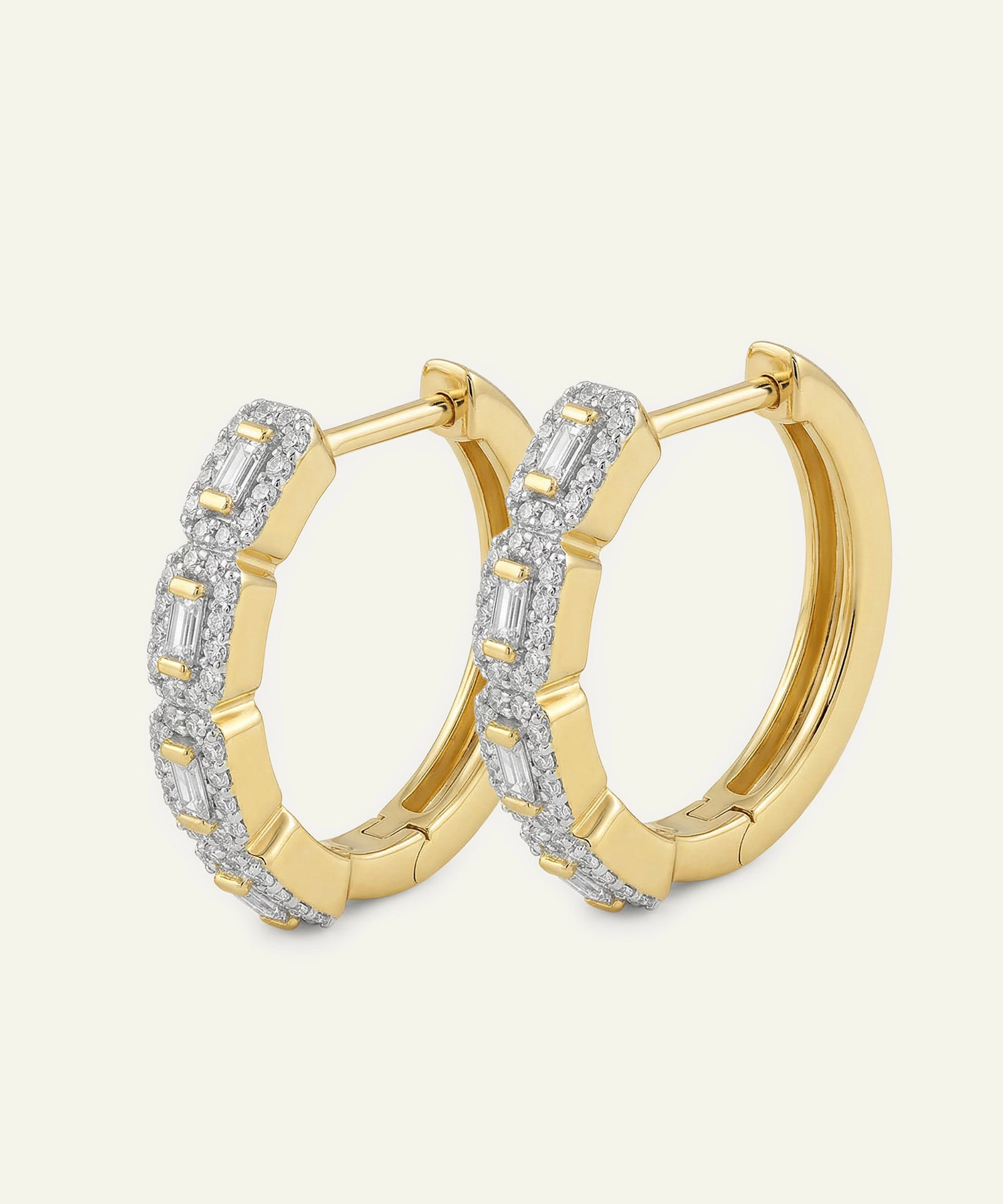 Gold hoop earrings with diamond accents on a light beige background