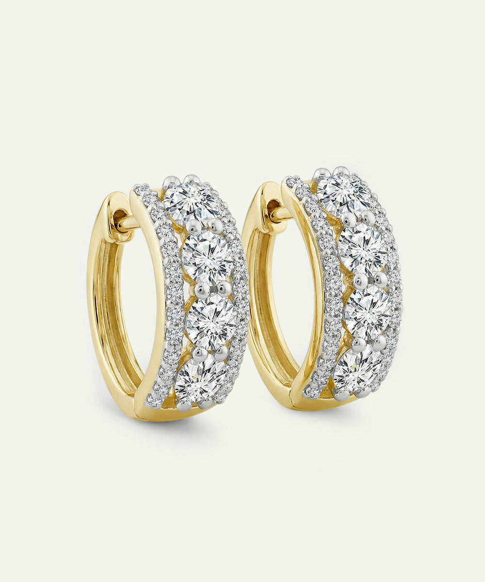 Gold hoop earrings with clear gemstones on a light gray background