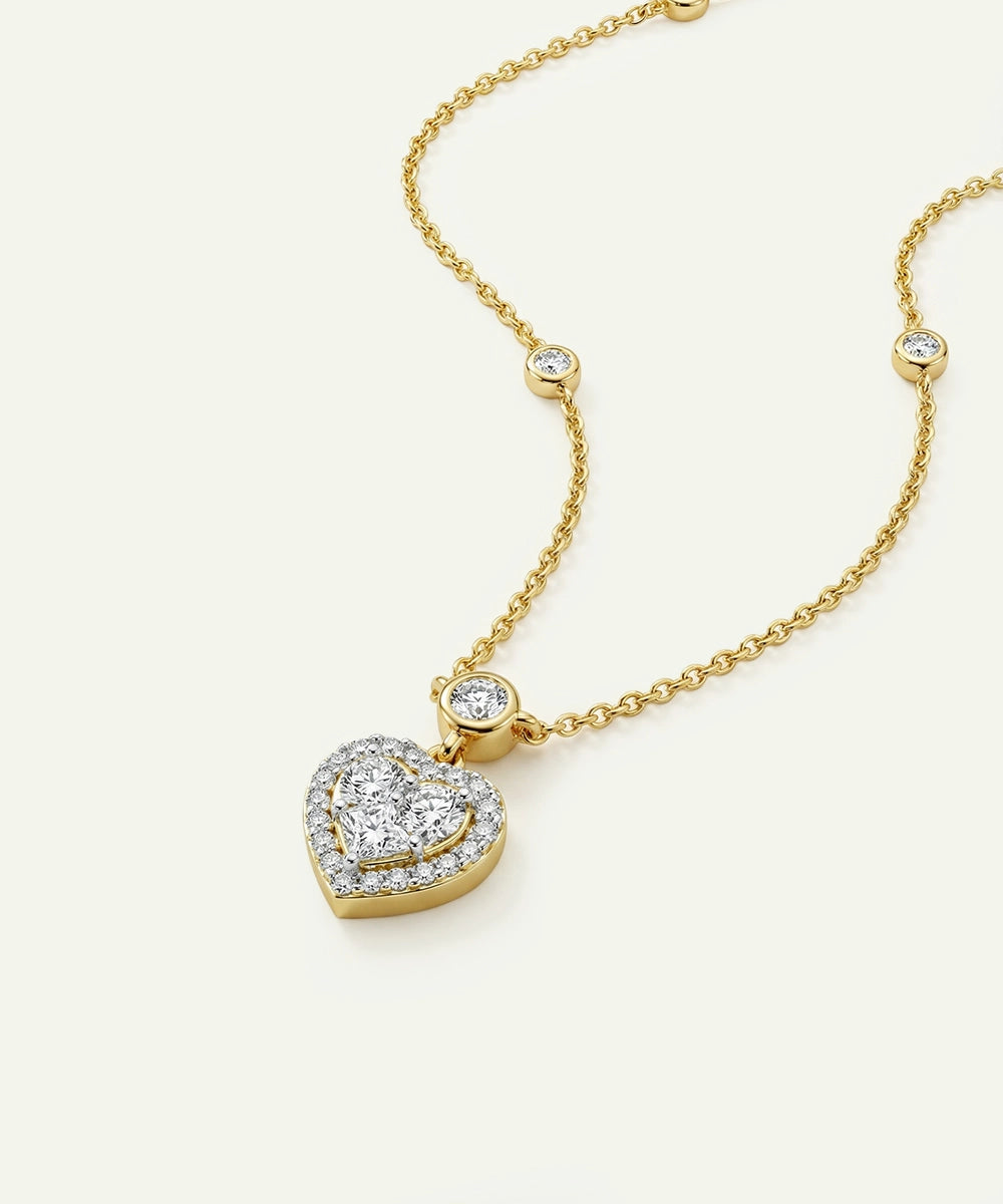 Gold necklace with a heart-shaped diamond pendant on a white background