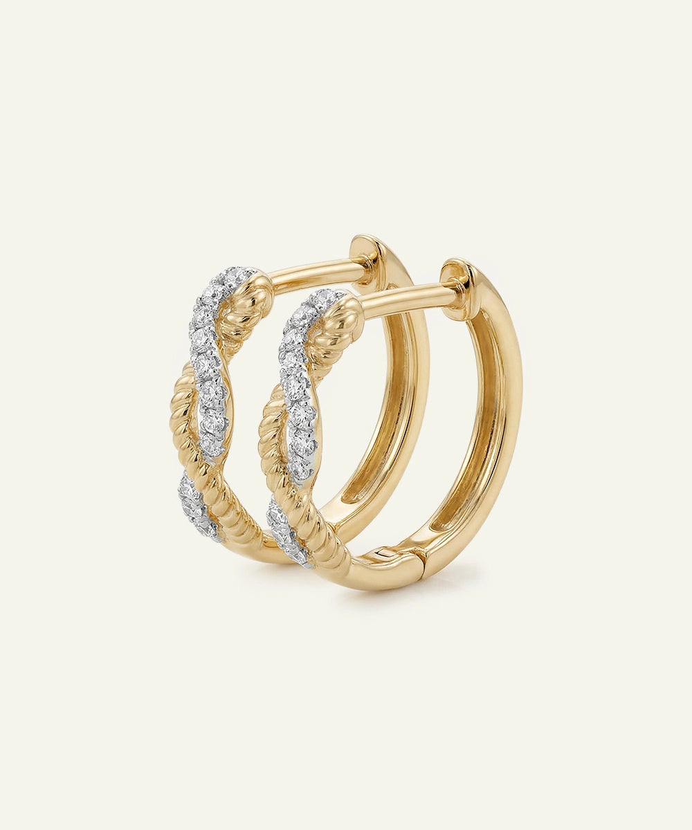Gold hoop earrings with diamond accents on a light beige background