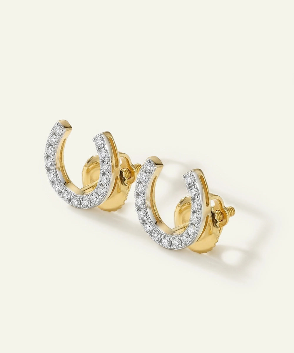 Gold earrings with clear gemstones on a light beige background