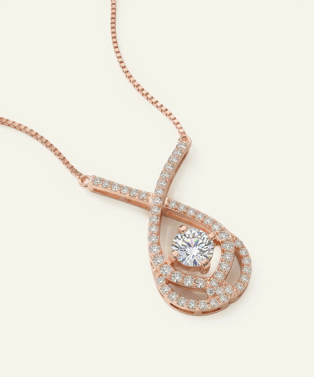 Rose gold necklace with a diamond pendant on a light beige background