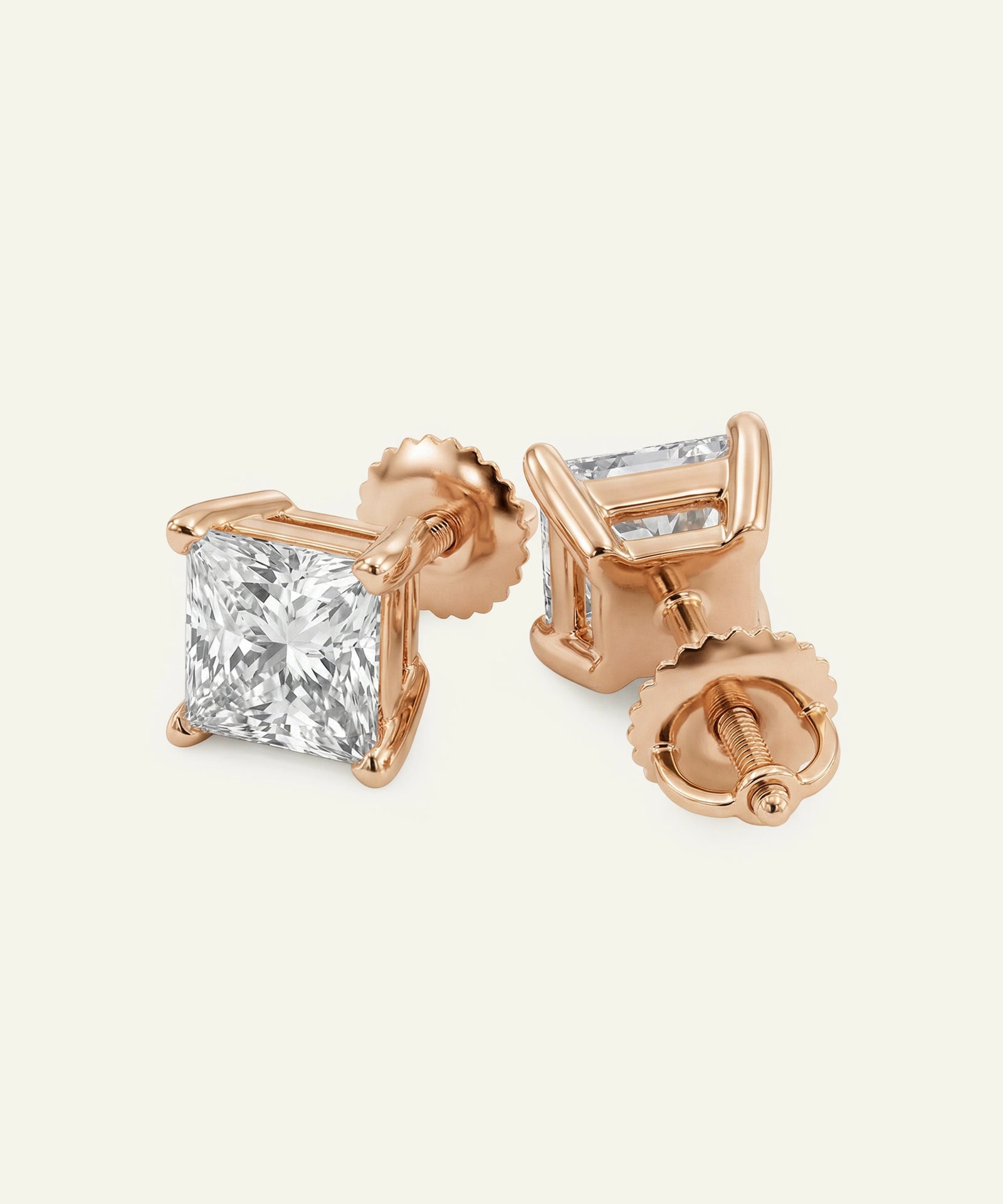 Rose gold stud earrings with clear gemstones on a light beige background