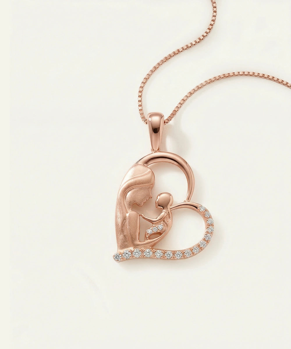 Rose gold heart-shaped pendant with a mother and child design on a light background