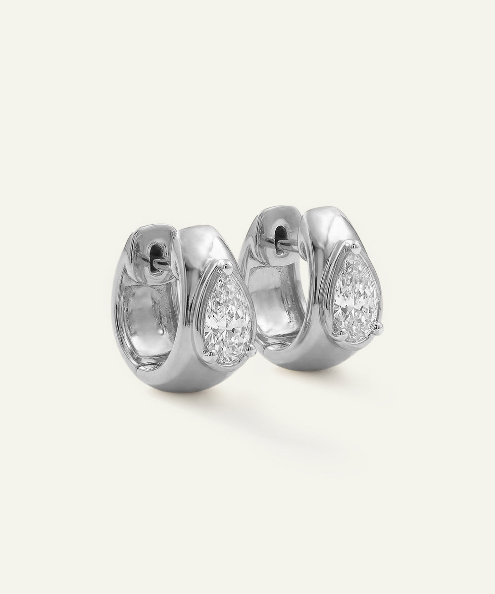 Pair of silver hoop earrings with clear gemstones on a light gray background