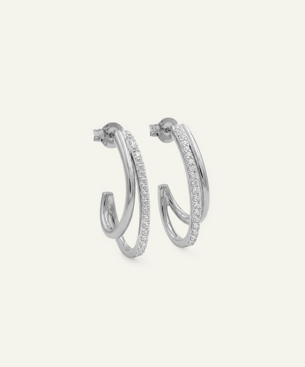 Silver hoop earrings with embedded stones on a light gray background