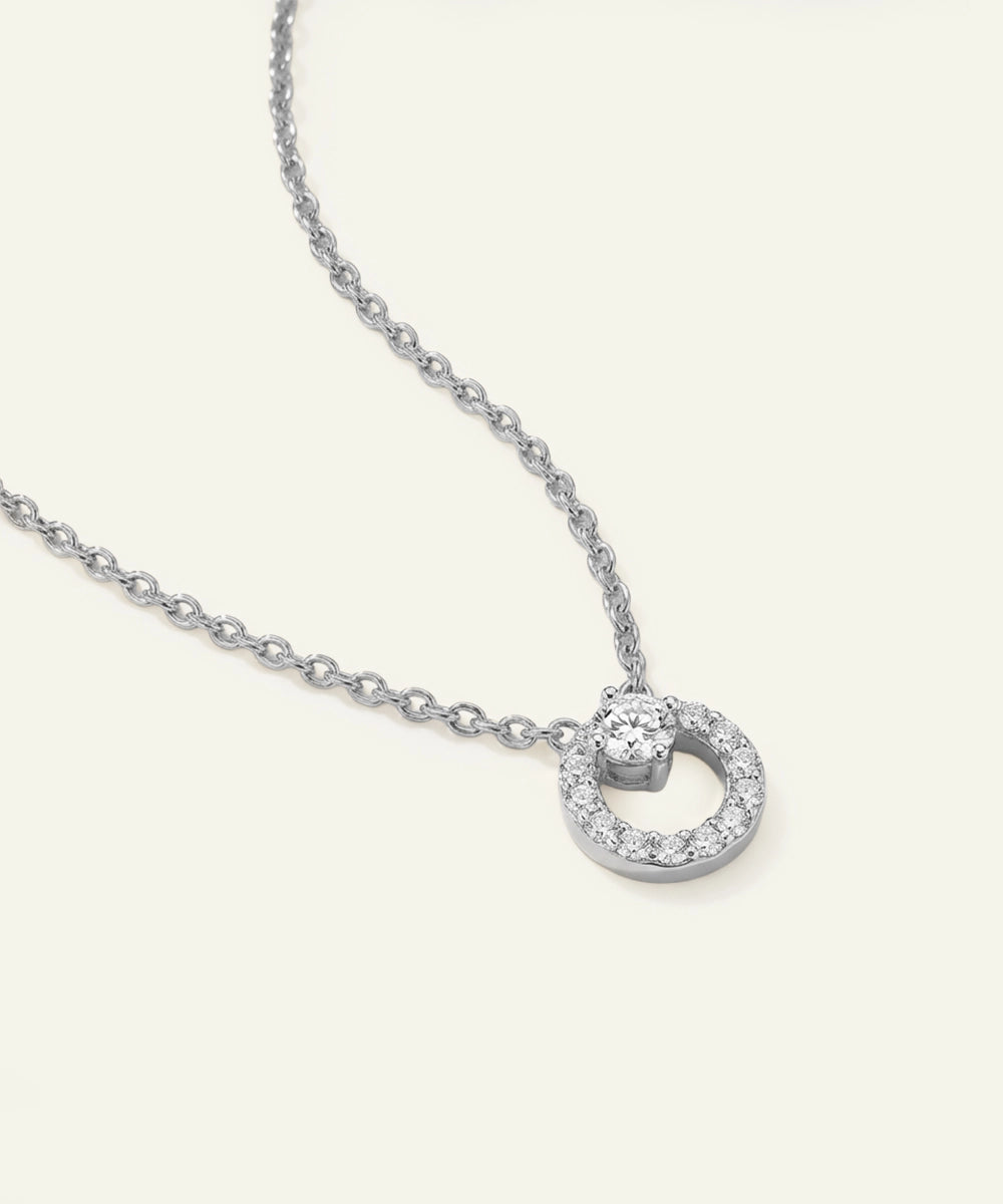 Silver necklace with a round pendant on a light gray background