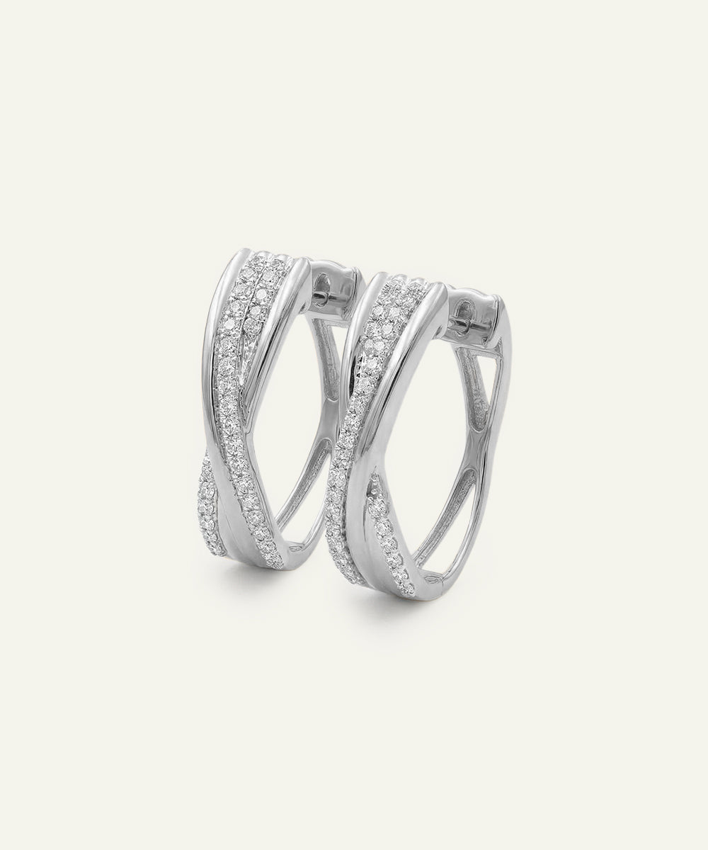 Pair of silver hoop earrings with clear gemstones on a white background