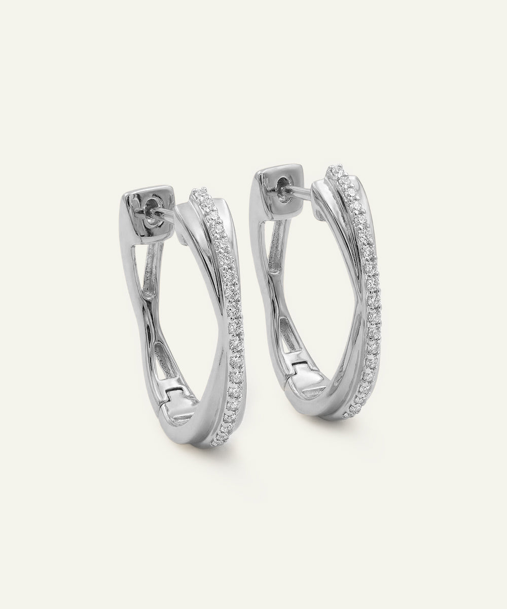 Pair of silver hoop earrings with embedded stones on a light gray background