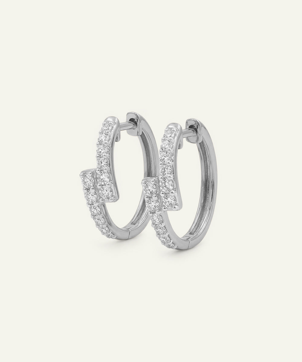 Pair of silver hoop earrings with clear gemstones on a light gray background