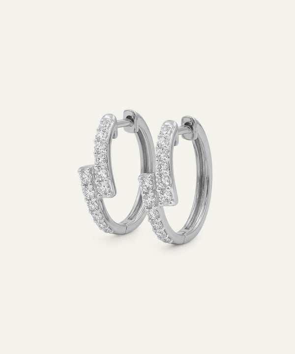 Pair of silver hoop earrings with clear gemstones on a light gray background