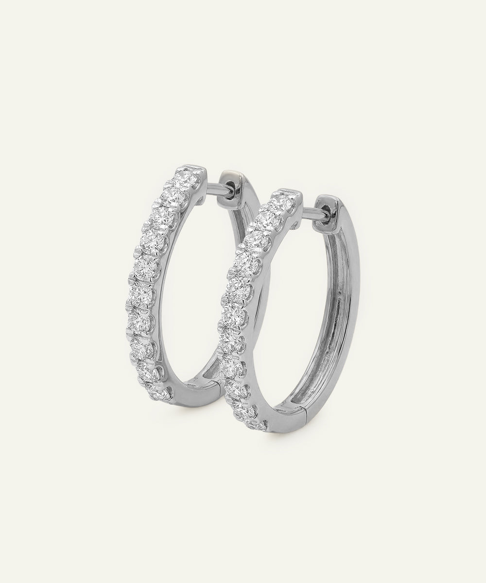 Silver hoop earrings with clear gemstones on a white background