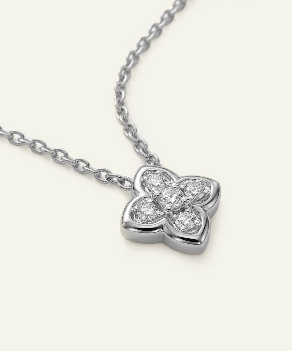 Silver necklace with a clover-shaped pendant on a white background