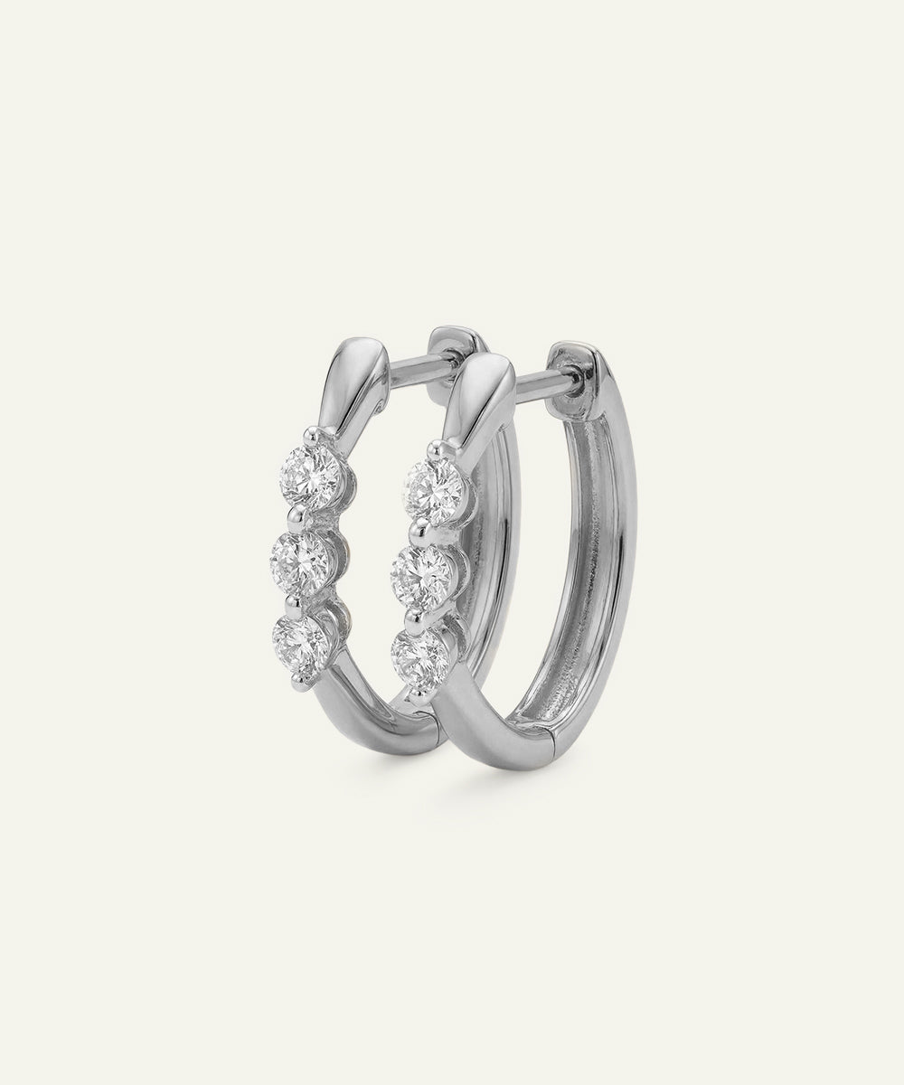 Silver hoop earrings with embedded stones on a light gray background