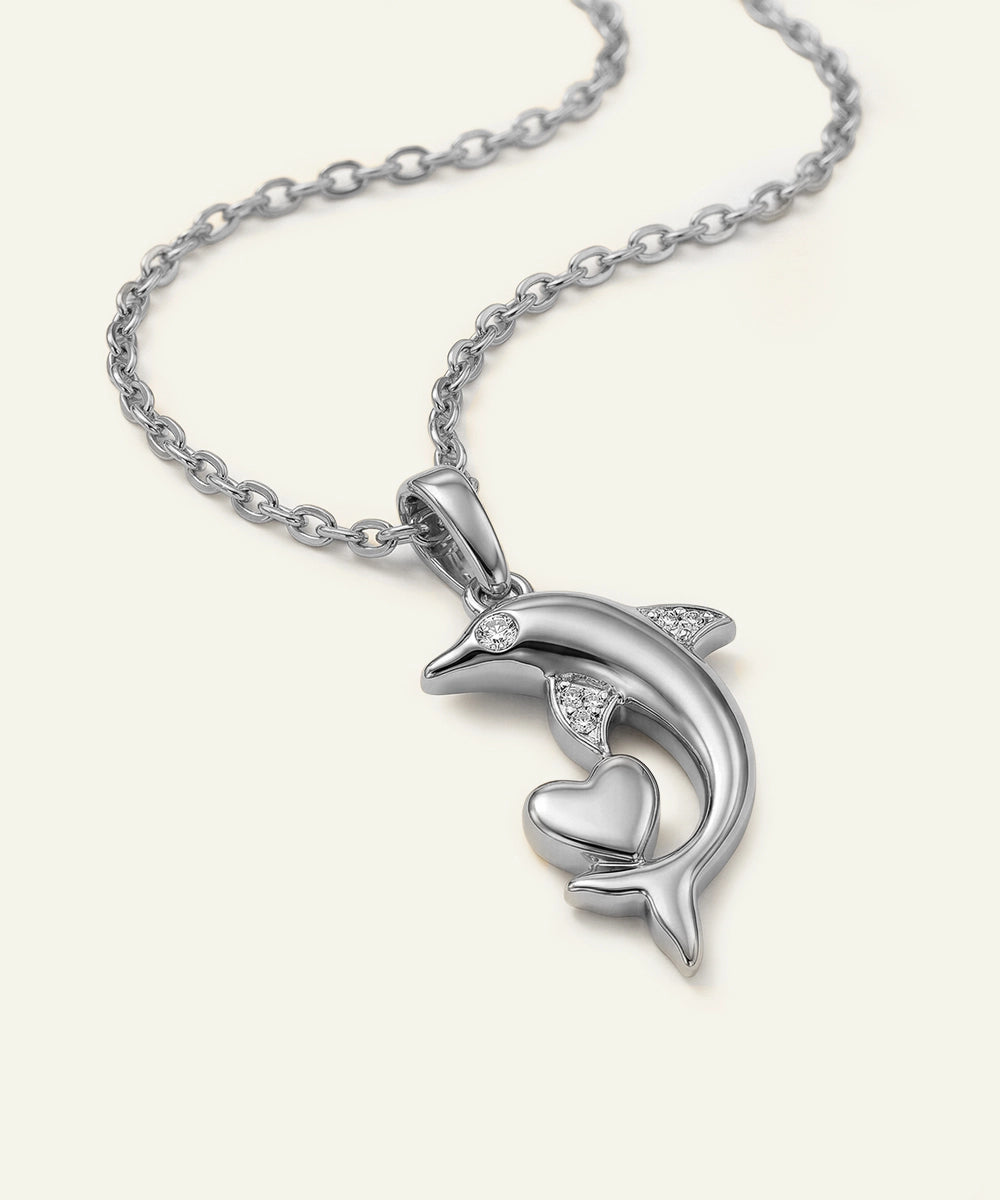 Silver dolphin pendant with heart on a chain against a white background